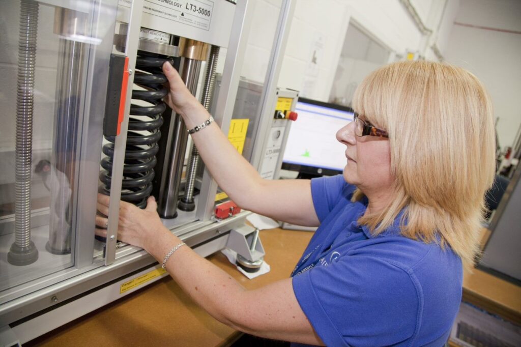 woman wearing goggles testing spring resistance on a machine